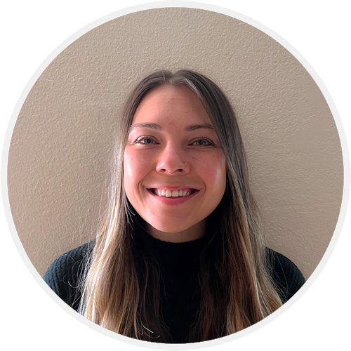 A woman smiling for the camera in front of a wall.